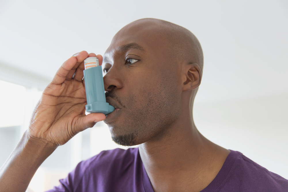Asthmatic person with an inhaler in his mouth.